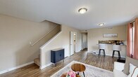 This two-bedroom, two-bathroom two-story home in Athens, Georgia offers a practical and comfortable layout spread across two well-proportioned floors. The main level features an open living area with warm-toned, wood-look flooring that flows seamlessly from the living room toward the kitchen. The living room is bright and welcoming, benefiting from natural light through windows dressed with curtains. A staircase with a white balustrade connects the floors, adding a clean architectural element to the space.

The kitchen is fully equipped with dark cabinetry, black appliances including a range, microwave, and refrigerator, complemented by granite-style countertops and a double basin sink. A peninsula with bar seating connects the kitchen to the main living area. A utility room and a bathroom are also located on this level.

Upstairs, two carpeted bedrooms provide a quiet retreat. The primary bedroom is generously sized and includes a walk-in closet, while the second bedroom also features dedicated closet storage. Each bedroom benefits from natural light through windows. A second full bathroom with a tub-shower combination and wood-look flooring serves the upper level.

Throughout the home, textured ceilings, neutral warm-beige walls, and multiple closets across both floors add to the functional and comfortable character of this Athens residence.