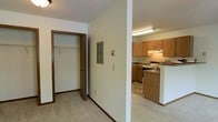 This single-floor space offers a straightforward and functional layout designed for practical everyday living. A central hallway connects the main areas, featuring neutral-toned carpeting and clean white walls accented by warm brown wood trim throughout. Along the hallway, a storage closet provides convenient organization space, complete with a hanging rod for clothing or general storage. An electrical panel is also accessible along this corridor, discretely integrated into the wall.

The kitchen is partially open to the hallway, creating a connected feel between spaces. It is equipped with medium-toned oak cabinetry offering generous storage, a white electric range, an under-cabinet range hood, and a peninsula or breakfast bar that helps define the kitchen area. The kitchen features hard-surface flooring, contrasting with the carpeted hallway. Overhead fluorescent lighting illuminates the workspace effectively.

The textured ceilings are consistent throughout, and the overall color palette — featuring warm wood tones against light walls and neutral flooring — creates a cohesive, utilitarian aesthetic. The space is well-suited for those seeking a no-frills, efficient layout with ample storage.