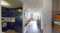Located on W Erie Street in Chicago's vibrant River North neighborhood, this single-floor unit offers a thoughtfully designed layout with a distinct, eclectic aesthetic. The open-concept living and dining area is a visual centerpiece, featuring rich dark hardwood flooring, a bold warm-toned accent wall with subtle pattern detailing, and large windows that frame impressive city skyline views. The space accommodates both a dining nook and a living area with ample room for seating and entertaining.

The kitchen is outfitted with dark espresso cabinetry, granite-style countertops, and black appliances including a range with overhead microwave, providing a sleek, functional workspace. A hallway connects the main living space to the private bedroom, which features plush carpeting, a deep teal accent wall, generous closet storage, and a window with additional city views.

The bathroom presents a clean, modern finish with a granite-topped vanity, dark cabinetry, a tiled tub-shower combination, and contemporary brushed nickel fixtures. Throughout the unit, textured ceilings, natural light, and a cohesive yet bold color palette contribute to a lively, urban ambiance well-suited to the heart of Chicago.