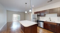 This 2-bedroom, 2-bathroom residence offers a thoughtfully designed single-floor layout that balances comfort and functionality. The open-concept kitchen and living area serves as the heart of the home, featuring rich dark-stained cabinetry, white countertops, a central island with pendant lighting overhead, and a full suite of stainless steel appliances including a refrigerator, range, microwave, and dishwasher. Wood-look flooring runs throughout the main living areas, adding warmth and continuity to the space.

The living room is bright and airy, benefiting from natural light that pours in through sliding glass doors leading to a private balcony with outdoor views. Both bedrooms are carpeted for comfort, with the generously sized primary bedroom featuring a dedicated closet and a window overlooking lush greenery. The second bedroom also offers plush carpeting, a ceiling-mounted track light fixture, and ample natural light.

Each bathroom is clean and functional, with wood-look flooring, a vanity with white countertops, and a walk-in shower. A dedicated laundry room houses a full-size washer and dryer, adding everyday convenience. Two hallways connect the living spaces efficiently, completing this well-organized and move-in-ready home.