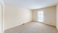 Located at 1810 W 76th St in Richfield, Minnesota, this single-level unit offers a straightforward, functional layout distributed across several well-defined spaces. The entryway greets residents with tile flooring and a sidelight window beside the front door, providing a welcoming transition into the interior.

The living areas feature a mix of flooring surfaces. A dining or flex room showcases light hardwood-style flooring and a sliding glass door fitted with vertical blinds, offering direct access to an outdoor area and allowing natural light to fill the space. A central ceiling fixture provides additional illumination. The remaining living and bedroom spaces are finished with neutral-toned carpet, contributing to a warm and quiet atmosphere throughout.

The bedrooms are generously proportioned, each featuring windows with horizontal blinds that admit natural light. One bedroom includes a sliding-door closet with a full-width hanging rod for practical storage.

The kitchen is equipped with rich, warm-toned wood cabinetry, granite-style countertops, a dishwasher, and a full-size refrigerator, all set atop matching hardwood-style flooring. The full bathroom features tile flooring, a wood-vanity with a granite-top sink, a large mirror, and a tub-shower combination enclosed by sliding glass doors. The overall ambiance is clean, neutral, and move-in ready.