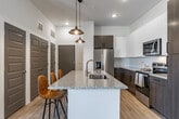 Located at 7 Vance Avenue in Memphis, Tennessee, this well-appointed residence offers two bedrooms, three bathrooms, a dedicated office, and three closets across a single floor. Light wood-style flooring runs throughout, creating a cohesive and airy feel.

The kitchen is a standout feature, showcasing a large granite-topped island with a built-in sink and pendant lighting overhead. Two-tone cabinetry—combining dark wood lower cabinets with crisp white uppers—frames a full suite of stainless steel appliances, including a French door refrigerator, electric range, and built-in microwave.

The generously sized primary bedroom features vaulted ceilings, a ceiling fan, and a window with plantation shutters that invite natural light. It is complemented by its own bathroom with a glass-enclosed shower and a spacious walk-in closet outfitted with multi-tier wire shelving systems. Additional closets throughout the home provide ample storage.

The secondary bedroom offers similarly bright, clean finishes with direct access to a full bathroom featuring a soaking tub and shower combination. A dedicated office space with clean white walls provides a quiet and functional work area. The bathrooms feature panel-style gray doors and light, neutral finishes that maintain a modern aesthetic throughout the home.