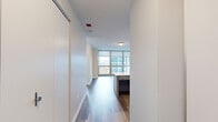 Located at 360 East South Water Street, this well-appointed residence offers a modern, single-level layout with clean finishes and an open, airy feel throughout. The living area is a standout feature, anchored by expansive floor-to-ceiling windows that flood the space with natural light and frame impressive views of the surrounding city skyline. Wood-style flooring runs throughout the main living areas, adding warmth and continuity to the design.

The kitchen is thoughtfully designed with white cabinetry, a subway tile backsplash, and a full suite of stainless steel appliances including a gas range, microwave, dishwasher, and refrigerator. A central island with a light quartz countertop provides additional prep space and a natural gathering point. The kitchen connects seamlessly to the living area, supporting an open-concept flow.

The bedroom offers a quieter retreat, featuring plush carpeting, a large built-in closet, and access to floor-to-ceiling windows that continue the theme of abundant natural light and skyline views.

The bathroom is finished with wood-look flooring, a gray vanity with a white countertop, a mirrored medicine cabinet, and a tub-shower combination with white tile surround and accessible grab bars. The entry hallway provides additional closet storage, completing this functional and contemporary urban residence.
