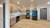 This single-floor, one-bedroom, one-bathroom unit offers a thoughtfully designed layout that maximizes functionality and comfort. The open-concept kitchen and living area forms the heart of the space, where light hardwood flooring flows seamlessly throughout. The kitchen is well-equipped with light natural wood cabinetry, granite-look countertops, a stainless steel sink, and a full suite of black appliances including a refrigerator, range, over-the-range microwave, and dishwasher. Recessed lighting illuminates the kitchen and living area, creating a warm and inviting atmosphere. The living room is generously sized with plush carpeting and features a sliding glass door that provides direct access to an outdoor balcony, bringing in natural light and views of the surrounding area. The bedroom is a comfortable retreat finished with soft carpeting and a large window that allows ample natural light and exterior views. The bathroom is accessible via the hallway and includes a wood-toned vanity with a countertop sink, mirror, and light hardwood flooring. Two closets provide practical storage throughout the unit. Clean neutral wall tones and warm wood accents give the entire space a cohesive, move-in-ready aesthetic.