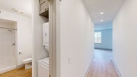 Located at 100 E Chestnut St in Rogers, Arkansas, this well-designed one-bedroom, one-bathroom unit offers a thoughtful layout across a single floor. Light-toned hardwood-style flooring runs throughout, creating a cohesive and clean aesthetic in every room.

The open-concept kitchen and living area serves as the heart of the unit. The kitchen is outfitted with gray shaker-style cabinetry, stainless steel appliances including a range, microwave, and dishwasher, a subway tile backsplash, and a single-basin sink. Large windows bathe the combined living space in natural light while providing views of the surrounding Rogers neighborhood.

The bedroom is a comfortable, well-proportioned space featuring a ceiling fan, a closet, and easy access to the adjoining living area, maintaining an open and connected flow. A hallway connects the main living spaces and includes a dedicated closet housing a stacked washer and dryer unit, adding in-unit laundry convenience.

The bathroom features light wood-style flooring consistent with the rest of the unit, a walk-in shower, a toilet, and a vanity with a framed mirror and taupe cabinetry with brushed nickel hardware. The overall design is clean and modern, with white walls and recessed lighting reinforcing a bright, contemporary ambiance throughout the space.