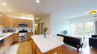This well-appointed two-bedroom, one-bathroom residence on University Avenue SE in Minneapolis offers a thoughtfully designed single-floor layout. The open kitchen and living area serve as the heart of the home, featuring warm honey-toned cabinetry, stainless steel appliances including a refrigerator, dishwasher, and range, as well as light countertops and recessed lighting. Durable hardwood-style flooring runs throughout the main living areas, complementing the bright, neutral palette. The living room is filled with natural light from large sliding glass doors that open directly onto a private balcony, offering pleasant views of surrounding greenery. A dedicated office nook provides a quiet workspace separate from the main living areas. The two bedrooms are carpeted and well-lit, each with windows that invite natural light. The primary bedroom offers comfortable proportions, while the second bedroom provides flexible use. The full bathroom features stone-tile flooring and walls, a combined shower and tub, and warm wood vanity cabinetry. A dedicated in-unit laundry area houses a stacked washer and dryer unit, adding everyday convenience. The overall ambiance is clean, functional, and inviting throughout.
