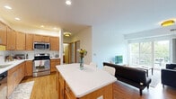 This well-appointed two-bedroom, one-bathroom residence on University Avenue SE in Minneapolis offers a thoughtfully designed single-floor layout. The open kitchen and living area serve as the heart of the home, featuring warm honey-toned cabinetry, stainless steel appliances including a refrigerator, dishwasher, and range, as well as light countertops and recessed lighting. Durable hardwood-style flooring runs throughout the main living areas, complementing the bright, neutral palette. The living room is filled with natural light from large sliding glass doors that open directly onto a private balcony, offering pleasant views of surrounding greenery. A dedicated office nook provides a quiet workspace separate from the main living areas. The two bedrooms are carpeted and well-lit, each with windows that invite natural light. The primary bedroom offers comfortable proportions, while the second bedroom provides flexible use. The full bathroom features stone-tile flooring and walls, a combined shower and tub, and warm wood vanity cabinetry. A dedicated in-unit laundry area houses a stacked washer and dryer unit, adding everyday convenience. The overall ambiance is clean, functional, and inviting throughout.