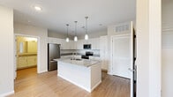 Located at 136 Lemon Dr in Lake Saint Louis, MO, this well-appointed one-bedroom, one-bathroom residence offers a thoughtfully designed single-floor layout. The kitchen serves as a standout centerpiece, featuring white shaker cabinetry, granite countertops, a subway tile backsplash, a large center island with an undermount sink, and stainless steel appliances including a refrigerator, range, microwave, and dishwasher. Three pendant lights hang above the island, adding both style and function. Light wood-style flooring flows throughout the main living areas, complementing the neutral color palette. The living room is bright and airy, with a ceiling fan, natural light from dual windows, and direct access to a private balcony with outdoor views. The bedroom offers plush carpeting, a ceiling fan, and access to a dedicated closet. The bathroom is finished with a granite-topped vanity, wood-style flooring, and a glass-enclosed tiled shower. A dedicated in-unit laundry area with a top-loading washer provides added convenience. Clean lines, modern finishes, and a cohesive neutral palette give this residence a fresh, move-in-ready appeal.