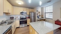 This single-floor residence at 900-912 S Market St in Wilmington, Delaware, offers a thoughtfully designed layout that balances functionality and contemporary style throughout. The open floor plan is revealed in the 3D overview, showcasing a generous living area, dedicated dining space, full kitchen, multiple bedrooms, and two full bathrooms.

The living area is bright and welcoming, with natural light filtering through large windows fitted with horizontal blinds, and wood-style flooring that extends consistently throughout the unit. A comfortable sectional sofa and wall art contribute to the relaxed ambiance of the space.

The dining area accommodates a round dark-wood table with upholstered seating, while a second dining space features a rectangular table with additional seating and a wall-mounted art piece nearby.

The kitchen is well-appointed with light wood cabinetry, granite-style countertops, stainless steel appliances including a refrigerator, electric range, and microwave, plus a central island for additional prep space and a built-in desk area near a window.

Bedrooms feature wood-style flooring, ample natural light, and closet storage. Both bathrooms include tub-shower combinations, dark-framed vanity mirrors, dark cabinetry, and large-format tile flooring.