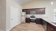 Located at 6102 Vermillion Cedar Way in Kannapolis, NC, this single-story 2-bedroom, 2-bathroom home offers a well-designed, functional layout with consistent neutral tones and quality finishes throughout. The open-concept living and kitchen area is anchored by durable wood-look flooring, vaulted ceilings, and abundant natural light streaming through multiple windows. A glass-paneled exterior door adds additional brightness and outdoor connectivity to the living space. The kitchen is appointed with rich dark cabinetry, granite-look countertops, and stainless steel appliances, including a refrigerator, range, and microwave. The primary bedroom features vaulted ceilings, wood-look flooring, a ceiling fan, and generous windows with wooded views. The second bedroom offers plush carpeting, a ceiling fan, and its own window for natural light. Both bathrooms are finished with dark wood vanities, granite-look countertops, and wood-look tile flooring; one includes a full tub-shower combination. Two closets provide ample storage. The attached garage is spacious, equipped with an automatic opener, and includes interior access. This home combines practical design with comfortable living in a well-appointed single-level floor plan.
