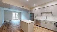 Located at 111 N Madison Ave in Pasadena, CA, this thoughtfully designed one-bedroom, one-bathroom residence offers a comfortable and modern living experience across a single floor. The open-concept kitchen and living area serves as the heart of the home, where light wood-tone flooring and a neutral color palette create a bright, welcoming atmosphere. The kitchen is well-appointed with gray shaker-style cabinetry, white quartz countertops, a classic subway tile backsplash, and a full suite of stainless steel appliances including a gas range, built-in microwave, dishwasher, and refrigerator. A center island provides additional prep space and casual seating. The living area benefits from natural light and opens to a private balcony through elegant French doors. The bedroom features plush carpeting, a window with views of surrounding greenery, and ample wall space. It connects conveniently to the hallway, which leads to the full bathroom. The bathroom is finished with large-format tile flooring, a wide vanity with white countertops and gray cabinetry, and a well-lit mirror. Clean lines and cohesive finishes throughout give this residence a polished, move-in-ready feel.