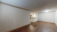 This single-floor unit offers a practical and well-organized layout designed for comfortable everyday living. The main living and dining area is expansive and open, finished with rich, dark hardwood-style flooring that extends throughout much of the unit. Crisp white walls and crown molding trim add a clean, polished character to the space, while a large window near the entry door allows natural light to filter in, brightening the interior.

The kitchen is positioned at the back of the living area and features a pass-through bar that connects it to the main living space, promoting an open and social atmosphere. Warm wood cabinetry, granite-style countertops, and a black electric range with an overhead ventilation hood provide a functional and cohesive cooking environment.

The bedroom is a generously sized, carpeted retreat, offering a comfortable and quiet atmosphere. A ceiling fan with integrated lighting provides both ventilation and illumination, making the room practical year-round.

The bathroom is neatly appointed with a rich wood vanity, granite-style countertop, a tiled shower-tub combination, and hardwood-style flooring that ties the space together with the rest of the unit. Overall, the unit presents a cohesive, move-in-ready interior with durable finishes and a straightforward, functional design.