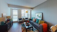 This single-floor residence on Austin Street NE in Blaine, Minnesota, offers a thoughtfully designed open-concept layout that connects the kitchen, dining, and living areas seamlessly. The kitchen is a functional highlight, featuring warm maple cabinetry, granite-style countertops, a central island with bar seating, and white appliances including a refrigerator, dishwasher, range, and microwave. Light wood-style flooring runs throughout the main living areas, contributing to a bright and cohesive aesthetic.

The living room is generously proportioned, bathed in natural light from large windows dressed with vertical blinds. Neutral gray walls provide a versatile backdrop, while hardwood-style flooring adds warmth to the space.

The bedroom offers plush carpeting, ample closet space, and a window that allows for natural light. Its layout comfortably accommodates full bedroom furnishings while maintaining an open feel. The bathroom features a clean, white tiled walk-in shower with a curtain enclosure and simple, functional fixtures. Overall, the residence presents a practical and comfortable living environment suited for everyday living in a well-maintained Blaine community.