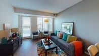 This single-floor residence on Austin Street NE in Blaine, Minnesota, offers a thoughtfully designed open-concept layout that connects the kitchen, dining, and living areas seamlessly. The kitchen is a functional highlight, featuring warm maple cabinetry, granite-style countertops, a central island with bar seating, and white appliances including a refrigerator, dishwasher, range, and microwave. Light wood-style flooring runs throughout the main living areas, contributing to a bright and cohesive aesthetic.

The living room is generously proportioned, bathed in natural light from large windows dressed with vertical blinds. Neutral gray walls provide a versatile backdrop, while hardwood-style flooring adds warmth to the space.

The bedroom offers plush carpeting, ample closet space, and a window that allows for natural light. Its layout comfortably accommodates full bedroom furnishings while maintaining an open feel. The bathroom features a clean, white tiled walk-in shower with a curtain enclosure and simple, functional fixtures. Overall, the residence presents a practical and comfortable living environment suited for everyday living in a well-maintained Blaine community.