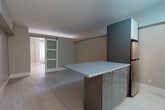 Located at 2166 Boulevard De Maisonneuve Ouest in Montréal, this one-bedroom, one-bathroom unit offers a thoughtfully designed layout that maximizes every square foot of its compact footprint. Light wood laminate flooring runs throughout, lending a bright, cohesive feel to the entire space.

The kitchen is a standout feature, showcasing sleek, modern cabinetry with reflective grey-toned doors, white upper cabinets, and a central island with a clean white countertop that doubles as a dining or prep surface. Stainless steel appliances complete the contemporary look. The kitchen flows naturally into the open living area, creating a practical and social layout.

A stylish sliding barn door with frosted glass panels serves as a partition, adding a modern architectural touch while connecting the living space to the bedroom corridor. The bedroom is a well-proportioned retreat with soft neutral walls, light flooring, and a built-in closet with double doors for ample storage. A window dressed with floor-length curtains allows natural light to filter in softly.

The bathroom is finished in crisp white tile, featuring a full soaking tub with a shower enclosure and a clean vanity with sink — simple, functional, and well-maintained. Overall, this unit presents a modern, minimalist aesthetic in a prime Montréal location.