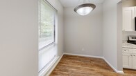 This single-story home in Columbus, GA (31907) offers a practical and comfortable layout with five bedrooms, two full bathrooms, a kitchen, dining room, hallway, and four closets. The galley-style kitchen is a standout feature, showcasing white shaker cabinetry, granite-look countertops, a subway tile backsplash, stainless steel appliances including a refrigerator and microwave, and durable hardwood-style flooring. The adjacent dining area benefits from a large window with blinds that allows ample natural light and views of surrounding greenery, complemented by a modern pendant light fixture. The generously sized primary bedroom features plush carpeting, a ceiling fan with light, a sliding closet, and direct access to a private bathroom with a vanity and tub-shower combo. The additional bedrooms are well-proportioned, each with soft carpeting and ceiling fans for comfort. Both bathrooms are clean and functional, featuring tub-shower combinations and hardwood-style flooring. Storage is well-addressed throughout, with multiple closets including a walk-in closet with wire shelving. The home maintains a neutral, warm color palette of soft beige and white tones, creating a cohesive and inviting ambiance throughout.