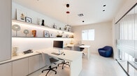 Located at 6190 Rock Island Rd in Tamarac, Florida, this professionally designed business center offers a clean, contemporary workspace environment. The single-floor layout is efficiently organized to maximize productivity and functionality within a compact footprint.

The interior design follows a minimalist aesthetic, dominated by a crisp white palette across the walls, ceilings, and built-in cabinetry. A central island-style workstation provides multiple workpoints, complemented by additional L-shaped desk configurations along the perimeter. Modern ergonomic seating and a navy blue accent chair add subtle pops of color to the otherwise neutral space.

A wall-length floating shelf runs the length of one side, illuminated by integrated LED strip lighting beneath, and is dressed with framed artwork, decorative objects, and plants — adding warmth and personality to the professional setting. Built-in taupe cabinetry provides ample storage solutions.

Floor-to-ceiling glass partitions with frosted banding divide the space from an adjacent area, maintaining visual openness while offering a degree of privacy. Natural light filters in through windows fitted with roller shades, enhancing the bright and airy atmosphere. Pendant lighting in varied styles descends from the ceiling, adding design character. Light-toned flooring ties the entire space together, creating a cohesive and polished professional environment.