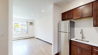 Located at 2727 S Rhode Island Ave in St. Louis Park, MN, this studio unit offers a practical and well-designed single-floor layout. The open-concept kitchen and living area forms the heart of the space, finished with warm light hardwood flooring that extends throughout. The kitchen is well-appointed with rich dark wood cabinetry, light countertops, and a full suite of stainless steel appliances including a refrigerator, electric range, and over-the-range microwave. A stainless steel sink with a modern faucet completes the functional kitchen setup. The living area is bright and open, featuring recessed lighting and a large window that invites natural light and provides outdoor views of the surrounding neighborhood. A wall-mounted air conditioning unit and baseboard heating ensure year-round comfort. The bathroom features a clean, all-white aesthetic with classic square tile surrounding the tub/shower combo, mosaic tile flooring, and crisp white walls, creating a tidy and functional space. Throughout the unit, white walls and light flooring contribute to an airy, open feel that maximizes the sense of space. This unit offers a streamlined, efficient living environment well-suited for those seeking a low-maintenance space in St. Louis Park.