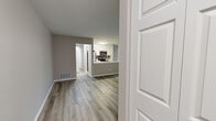 Located at 1423 E Evergreen Dr in Palatine, IL, this single-floor, one-bedroom, one-bathroom residence offers a thoughtfully designed layout finished with contemporary details throughout. Light wood-tone luxury vinyl plank flooring runs continuously across all rooms, creating a cohesive and clean aesthetic. Neutral warm-gray walls complement the bright white trim and panel doors, lending the space a modern yet inviting character.

A standout feature is the pair of glass-paned French doors that connect the living room to the adjoining spaces, allowing natural light to flow freely and adding architectural elegance. The living room is generously proportioned, with large windows dressed in vertical blinds that provide ample natural light and outdoor views. A sliding glass door further enhances the brightness of the main living area.

The kitchen features white cabinetry, white quartz countertops, a gray subway tile backsplash, and a full suite of stainless steel appliances including a range, microwave, dishwasher, and refrigerator. A peninsula counter opens toward the living space, reinforcing the open-concept feel.

The bedroom is comfortably sized with a large window and direct access to a laundry area. The bathroom includes a white vanity, tiled tub-shower combination, and wood-tone flooring, completing the space with clean, functional design.