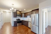 Located at 225 Sandwich St N in Amherstburg, Ontario, this well-appointed 2-bedroom, 2-bathroom single-floor residence offers a comfortable and modern living experience. Rich hardwood-style flooring flows consistently throughout the entire unit, creating a warm and cohesive aesthetic.

The kitchen is a standout feature, showcasing rich dark-walnut cabinetry with sleek hardware, light granite countertops, a classic white subway tile backsplash, and a full suite of stainless steel appliances including a French door refrigerator, electric range with over-the-range microwave, and dishwasher. An elegant chandelier adds a refined touch to the space.

The open layout connects the kitchen to the living area, which benefits from natural light through large windows dressed with vertical blinds. The generously sized primary bedroom includes a sliding double closet with arched panel doors. A dedicated closet space offers additional storage throughout the unit.

Both bathrooms are finished with granite-topped vanities and wood-style flooring. The main bathroom features a full soaker tub and shower combination. A hallway leads to a private ensuite with a well-lit vanity and mirror.

A dedicated laundry room with a full-size washer and dryer adds everyday convenience, completing this thoughtfully designed home.