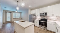 Located at 2470 Cherry Laurel Dr in Sanford, Florida, this single-story residence offers a contemporary design with a clean, neutral color palette throughout. The open-concept kitchen serves as a central highlight, featuring white shaker-style cabinetry extending to the ceiling, a subway tile backsplash, and a full suite of stainless steel appliances including a refrigerator, electric range, and built-in microwave. A large central island with quartz countertops and an undermount sink anchors the space, illuminated by stylish globe pendant lights. The kitchen flows seamlessly into the living area, where wood-style plank flooring, a ceiling fan, and a window with blinds create a bright, functional setting.

The bedrooms are finished with plush carpeting, ceiling fans, and windows that allow natural light to filter in. One additional room features the same wood-style flooring, offering flexible use as a living or dining space with direct access to a glass-panel door leading outside.

The bathroom is elegantly appointed with large-format marble-look tile on both the floor and tub surround, a white vanity with quartz countertops, and a frameless mirror. A dedicated laundry area houses a full-size top-loading washer and dryer with overhead shelving for added storage convenience.