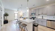 Located at 3755 E McKinney St in Denton, TX, this one-bedroom, one-bathroom unit offers a thoughtfully designed single-floor layout with modern finishes throughout. The open-concept kitchen is a standout feature, equipped with grey shaker-style cabinetry, granite countertops, a stainless steel appliance suite including a French door refrigerator, electric range, built-in microwave, and dishwasher, as well as light wood-look flooring and a peninsula island with bar seating — ideal for casual dining or entertaining. The living room is bright and welcoming, highlighted by a transom-windowed exterior door that invites natural light and outdoor views, complemented by a ceiling fan and light wood flooring. The bedroom features plush carpet, dual windows overlooking the outdoors, a ceiling fan, and direct access to a walk-in closet with built-in shelving. A second closet provides additional storage. The bathroom is finished with the same grey cabinetry and granite countertop vanity, light flooring, and a shower-tub combination. Clean white walls and consistent modern hardware tie the entire space together for a cohesive, contemporary feel.