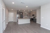 This single-floor residence showcases a cohesive contemporary design with thoughtful finishes carried throughout each space. The kitchen serves as a central highlight, featuring flat-front dark cabinetry extending to the ceiling, light quartz countertops, subway tile backsplighting, stainless steel appliances, and a generous island with bar seating. Recessed lighting and pendant fixtures illuminate the space, while light wood-look flooring flows seamlessly underfoot.

The living area offers a welcoming, open layout with the same warm wood-look flooring, neutral walls, and ample room for comfortable furnishings. Multiple bedrooms provide restful retreats, each carpeted for comfort. The primary bedroom features a bold navy accent wall, ceiling fan, and natural light from a window with draping curtains. Additional bedrooms maintain a calm, neutral palette with soft carpet and practical storage space.

Two full bathrooms mirror each other in style, each appointed with dark vanity cabinetry, light quartz countertops, wood-look flooring, and a tiled tub-shower combination with subway tile surround. The overall ambiance throughout is modern and refined, with a consistent palette of dark cabinetry, neutral tones, and clean architectural lines.