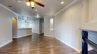 This single-story, 3-bedroom, 2-bathroom home offers a thoughtfully designed layout with a comfortable and functional living experience. The open-concept living and kitchen area serves as the heart of the home, featuring warm hardwood-style flooring, crown molding, recessed lighting, and a ceiling fan. A fireplace anchors the living room, complemented by a built-in arched niche and access to a private balcony that overlooks a lush, tree-lined landscape. The kitchen is equipped with warm wood cabinetry, granite countertops, a stainless steel refrigerator with ice maker, and a stylish pendant light fixture above the breakfast bar. Each of the three bedrooms is carpeted for comfort and includes closet storage, with ceiling fans providing additional airflow. The primary bedroom features a walk-in closet with built-in shelving. The bathrooms are well-appointed, with one showcasing a tiled walk-in shower with a built-in bench seat and large-format stone-look tile. A dedicated laundry area and multiple hallways add to the home's practicality. The neutral color palette and clean finishes throughout create a bright, move-in-ready atmosphere.