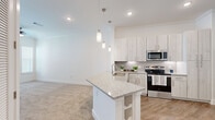 Located in Katy, TX, this 1-bedroom, 1-bathroom residence offers a thoughtfully designed layout that maximizes every square foot. The open-concept kitchen serves as the heart of the home, showcasing light wood-toned cabinetry that extends to the ceiling for ample storage, granite-look countertops, a subway tile backsplash, and stainless steel appliances including a range, microwave, and refrigerator. A peninsula island with an undermount sink and pendant lighting above creates a natural divide between the kitchen and the carpeted living area, making the space feel open and connected. The bedroom is a comfortable retreat featuring soft carpet flooring, a ceiling fan, and a window that brings in natural light. It offers direct access to both the full bathroom and a dedicated closet. The bathroom is finished with wood-look vinyl flooring, a granite-top vanity with white cabinetry, and a glass-enclosed walk-in shower accented with dark tile surround. A separate laundry area accommodates a full-size washer and dryer with overhead shelving, adding everyday convenience. The consistent use of white walls and bright finishes throughout lends the space a clean, modern aesthetic.