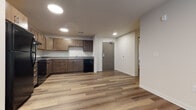 Located at 1318 E Washington Ave in Madison, Wisconsin, this single-floor unit offers a well-designed layout with contemporary finishes and a functional, open feel. The space is characterized by durable wood-look plank flooring throughout the main living areas, recessed lighting, and clean white walls that create a bright, modern atmosphere.

The kitchen is a standout feature, offering ample cabinetry in a warm walnut-toned finish, generous counter space with neutral gray laminate surfaces, and a full suite of black appliances including a refrigerator, range with overhead ventilation, and dishwasher. The kitchen's L-shaped layout provides excellent workspace and flows openly into the main living area.

Bedroom spaces feature soft carpeting and windows fitted with vertical blinds, allowing for natural light while maintaining privacy. The unit includes two bathrooms: a full bath with a tub-shower combination, a vanity with a white countertop, and a large mirror, as well as a half bath featuring similar dark cabinetry and wood-look flooring.

A dedicated in-unit laundry area houses a full-size front-loading Whirlpool washer and dryer with overhead wire shelving for added storage. The overall design is clean, modern, and practical, making this a well-appointed space in Madison's vibrant East Washington corridor.