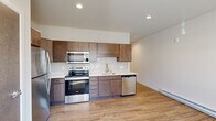 Located at N72 W12727 Good Hope Rd in Menomonee Falls, Wisconsin, this efficiently designed single-floor unit offers a well-appointed layout that maximizes every square foot. Light wood-look plank flooring runs throughout the space, lending warmth and cohesion to the interior.

The kitchen is a standout feature, outfitted with rich medium-toned wood cabinetry extending to the upper walls for generous storage. A full suite of stainless steel appliances includes a refrigerator, electric range, built-in microwave, and dishwasher. Light-toned countertops and a classic white subway tile backsplash complete the clean, modern aesthetic, while recessed lighting ensures the space is well-lit.

The bathroom is bright and functional, featuring light wood-look tile flooring, a single-sink vanity with a white countertop and wood cabinetry, and a full tub/shower combination with chrome fixtures set against crisp white walls.

The dedicated laundry area includes a stacked Whirlpool washer and dryer unit alongside wire shelving for additional storage, making the most of the available space.

Overall, the unit presents a contemporary, move-in-ready interior with consistent finishes, practical storage solutions, and a neutral palette that creates a clean and inviting atmosphere.