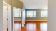 Located at 459 Locust Ave in Charlottesville, Virginia, this well-appointed one-bedroom, one-bathroom residence offers a thoughtfully designed single-floor layout. Rich hardwood flooring flows throughout the entire unit, lending warmth and continuity to every room.

The open-concept living, dining, and kitchen area forms the heart of the home. Large windows with horizontal blinds fill the space with generous natural light while offering pleasant outdoor views. A stylish pendant-lit kitchen island with a bold navy base and granite countertop serves as both a functional workspace and a visual centerpiece. The kitchen is fully equipped with white shaker cabinetry, granite countertops, and a full suite of stainless steel appliances, including a refrigerator, range, and built-in microwave.

The bedroom is a comfortable, well-lit retreat featuring a large window with outdoor views and direct access to a spacious walk-in closet outfitted with multi-level shelving and hanging rods. A second closet provides additional storage.

The bathroom is finished with tile flooring, a granite-topped vanity with dark wood cabinetry, a large mirror, and a full tub-shower combination with tile surround. An in-unit laundry area adds everyday convenience. The unit's neutral gray walls and clean finishes give it a modern, move-in-ready appeal.