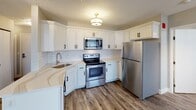 Located at 20 Sheldon Blvd SE in Grand Rapids, Michigan, this single-floor unit offers a thoughtfully updated interior with a clean, contemporary aesthetic throughout. The open living and dining area is anchored by durable wood-style flooring, soft gray walls, and textured ceilings, with multiple windows allowing generous natural light and urban views of the surrounding skyline to filter in.

The kitchen is well-appointed with white shaker-style cabinetry accented by matte black hardware, light quartz countertops, a classic subway tile backsplash, and a full suite of stainless steel appliances including a range, microwave, and refrigerator. A flush-mount light fixture adds a polished finishing touch.

The bedrooms are spacious and bright, each featuring the same wood-style flooring and large windows that frame views of the Grand Rapids cityscape, including a notable church steeple visible from one room.

The bathrooms are finished with marble-style tile flooring in a herringbone pattern, white vanity cabinetry with matte black fixtures, and a full tub-shower combination in the primary bath. Recessed and vanity lighting enhances the clean, modern feel throughout. The overall ambiance is fresh, functional, and urban.