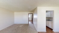 This single-story unit in Baton Rouge, Louisiana, offers a practical and straightforward layout across two bedrooms, one bathroom, a living room, dining room, and kitchen. The interior features a neutral color palette of cream and beige tones throughout, creating a clean, cohesive look.

The living room is carpeted and receives natural light through a window fitted with blinds, with a paneled entry door providing direct access. A textured popcorn ceiling is consistent throughout the carpeted areas of the unit. The spacious primary bedroom also features carpet flooring, while other rooms transition to wood-look laminate flooring, providing a contrast in texture and easy maintenance.

The second bedroom and additional rooms with laminate flooring share the same light-toned walls and textured ceilings. A wall-mounted air conditioning unit services one of the rooms, accompanied by a window for natural light.

The galley-style kitchen is efficiently organized with white cabinetry on both sides, a coil electric range, refrigerator, double stainless steel sink, and a dishwasher, all finished in white. The single full bathroom includes a tiled shower-tub combination and standard fixtures. Overall, the unit offers a functional, no-frills living environment.