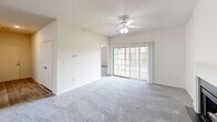 Located in Lake Saint Louis, Missouri, this well-appointed single-floor home offers three bedrooms, two bathrooms, and a thoughtfully designed layout. The spacious living room serves as the heart of the home, featuring plush carpeting, a ceiling fan, a classic wood-burning fireplace with a white mantle, and sliding glass doors that invite natural light and provide outdoor access. The open-concept kitchen is equipped with white cabinetry, dark granite-style countertops, a breakfast bar peninsula, and white appliances including a range, microwave, and refrigerator, with wood-look flooring tying the space together. A dedicated laundry room houses a full-size Whirlpool washer and dryer with built-in wire shelving above. The bedrooms are carpeted and bright, each featuring ceiling fans and windows with outdoor views of the surrounding greenery. The primary bedroom offers a generous footprint with ample closet space. Both bathrooms are finished with wood-look flooring, white vanities, and dark countertops; one features a full tub-shower combo. Two closets provide additional storage throughout the home, making this residence a practical and comfortable option in Lake Saint Louis.