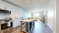Located at 7244 N Lincoln Ave in Lincolnwood, IL, this one-bedroom, one-bathroom unit offers a well-designed, modern interior across a single floor. The open-concept layout seamlessly connects the kitchen and living room, creating an efficient and cohesive living space.

The kitchen is outfitted with white flat-panel cabinetry extending to the ceiling, stainless steel appliances including a refrigerator, gas range, microwave, and dishwasher, and a clean white tile backsplash. A freestanding island with seating provides additional prep and dining space. Hardwood-style flooring runs throughout, adding warmth and continuity.

The living area benefits from large windows that invite abundant natural light and offer views of the surrounding tree-lined neighborhood. Neutral gray walls complement the contemporary finishes throughout the space.

The bedroom accommodates a comfortable furniture arrangement and features a large window with outdoor views, contributing to a bright and airy atmosphere. A dedicated closet provides practical storage.

The bathroom is finished with a white vanity, white quartz countertop, and a backlit LED mirror, maintaining the clean, modern aesthetic found throughout the unit. Wood-look flooring continues here, tying the space together cohesively.