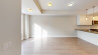 Located at 1265 Birchmount Rd in Toronto's Scarborough district, this well-appointed two-floor unit offers a bright, modern living experience across two thoughtfully designed levels. The main floor features a seamless open-concept layout connecting the kitchen, dining, and living areas. The kitchen is outfitted with sleek white cabinetry, a tiled backsplash, dark countertops, stainless steel appliances including a French door refrigerator and dishwasher, and a central island with a built-in sink accented by pendant lighting overhead. Light hardwood flooring flows throughout, complementing the neutral, warm-toned walls and contributing to an airy, cohesive aesthetic. The living area benefits from generous natural light streaming through large windows. The upper floor hosts additional rooms, including a bedroom with mirrored sliding closet doors and windows framing urban views of the surrounding Toronto skyline. A dedicated bathroom features a glass-enclosed walk-in shower with classic white subway tile. Rooms throughout the upper level enjoy abundant natural light via large windows and glass-paneled doors that open to outdoor views. Clean architectural lines, recessed tray ceiling detailing in the living area, and a consistent modern palette make this a polished, functional urban residence.