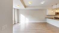 Located at 1265 Birchmount Rd in Toronto's Scarborough district, this well-appointed two-floor unit offers a bright, modern living experience across two thoughtfully designed levels. The main floor features a seamless open-concept layout connecting the kitchen, dining, and living areas. The kitchen is outfitted with sleek white cabinetry, a tiled backsplash, dark countertops, stainless steel appliances including a French door refrigerator and dishwasher, and a central island with a built-in sink accented by pendant lighting overhead. Light hardwood flooring flows throughout, complementing the neutral, warm-toned walls and contributing to an airy, cohesive aesthetic. The living area benefits from generous natural light streaming through large windows. The upper floor hosts additional rooms, including a bedroom with mirrored sliding closet doors and windows framing urban views of the surrounding Toronto skyline. A dedicated bathroom features a glass-enclosed walk-in shower with classic white subway tile. Rooms throughout the upper level enjoy abundant natural light via large windows and glass-paneled doors that open to outdoor views. Clean architectural lines, recessed tray ceiling detailing in the living area, and a consistent modern palette make this a polished, functional urban residence.