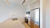 Located at 808 Cleveland Ave in Chicago's vibrant River North neighborhood, this modern one-bedroom, two-bathroom unit offers a well-designed layout across a single floor. The open-concept living area is anchored by dramatic floor-to-ceiling windows that flood the space with natural light and frame sweeping views of the Chicago skyline and surrounding cityscape. Light wood-tone flooring runs throughout, complementing the clean, contemporary aesthetic.

The kitchen features stainless steel appliances, including a full-size refrigerator, range, and built-in microwave, alongside two-tone cabinetry with natural wood accents, a white subway tile backsplash, and a generous quartz countertop island with an undermount sink — ideal for both meal prep and casual dining. Track lighting overhead adds a modern touch.

Both bathrooms are thoughtfully finished: one includes a walk-in shower with large-format tile surround, while the other offers a clean, minimalist design with a dark wood vanity, quartz countertop, and warm tile flooring. A dedicated laundry area houses a stacked washer and dryer unit for added convenience. The bedroom benefits from the same floor-to-ceiling window treatment, offering bright, open city views. Built-in shelving in the hallway provides practical storage within the compact footprint.