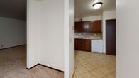 This single-floor unit offers a practical and well-organized layout throughout its living spaces. The kitchen is a standout feature, outfitted with rich, dark wood cabinetry extending from base to upper level, a tile backsplash in a diamond pattern, light countertops, a stainless steel sink, and a white dishwasher alongside a black electric range. The tile flooring in the kitchen transitions to neutral-toned carpet throughout the living and bedroom areas, lending warmth underfoot.

The spacious living area is open and bright, with white walls, baseboard heating, and windows fitted with horizontal blinds that allow natural light to filter in. A mirrored sliding closet door adds depth to one of the rooms, which also features a ceiling fan with a built-in light fixture. The bedroom includes a window with an outdoor view, baseboard heating, and generous wall space.

The bathroom is cleanly appointed with tile flooring, a tiled tub-and-shower surround, a dark wood vanity with a framed mirror, and wall-mounted lighting. A second full bathroom mirrors this layout. The overall ambiance of the unit is clean, neutral, and move-in ready.