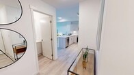 Located in Calgary's vibrant SW community, this thoughtfully designed one-bedroom, one-bathroom unit offers a bright and contemporary living experience. Light hardwood flooring flows throughout, complementing the clean white walls and modern finishes that define the space.

The entryway welcomes you with a sleek glass console, opening into the combined kitchen and living area. The kitchen is a standout feature, boasting light wood cabinetry, a white quartz countertop with a large breakfast bar, stainless steel appliances including a French door refrigerator, electric range, built-in microwave, and dishwasher, as well as a classic subway tile backsplash. The layout is both functional and visually open.

The living area is anchored by floor-to-ceiling windows that flood the space with natural light and frame sweeping panoramic city skyline views. The bedroom continues this connection to the outdoors with its own expansive windows offering stunning high-rise cityscape vistas, creating a serene and airy retreat.

The bathroom is finished with clean, neutral tones, featuring a glass-enclosed shower, light wood vanity, and white quartz countertop. A conveniently located hallway provides access to all rooms, ensuring an efficient and well-organized floor plan throughout.