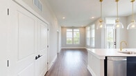 Located at 2130 Wilkinson Blvd in Charlotte, NC, this thoughtfully designed single-floor residence offers two bedrooms and three bathrooms within a well-appointed floor plan. The interior is finished with warm hardwood-style flooring and neutral gray walls throughout, creating a clean, cohesive aesthetic.

The kitchen serves as a central highlight, featuring a large waterfall-edge quartz island with an integrated sink, dark navy lower cabinetry paired with wood-toned upper cabinets, brass hardware accents, stainless steel appliances including a refrigerator and range, a wall-mounted range hood, and glass pendant lighting. Multiple windows flood the space with natural light and offer views of the surrounding Charlotte skyline and greenery.

The bedrooms are bright and spacious, with large windows providing outdoor views and hardwood-style flooring throughout. Each room includes access to well-organized closets fitted with wire shelving systems. The primary bedroom features its own dedicated closet space.

The bathrooms are elegantly finished, with marble-look tile flooring, wood-toned vanities, white quartz countertops, and brass fixtures. One bathroom showcases a dramatic dark herringbone-tiled tub surround, while another features a black-framed mirror and contemporary vanity lighting, adding a refined, modern touch to the overall design.