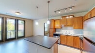 Located at 1000 Ashwood Pkwy in Atlanta, Georgia, this single-floor residence offers a thoughtfully designed layout with a seamless flow between its living and functional spaces. The open-concept kitchen is a standout feature, showcasing warm honey-toned wood cabinetry, granite countertops, a subway tile backsplash, and a full suite of stainless steel appliances including a range, microwave, dishwasher, and refrigerator. Track lighting and dual pendant lights over the central island provide both task and ambient illumination. The kitchen opens directly to a generously sized living area finished with light wood-style flooring and crown molding throughout, creating a cohesive and polished aesthetic. Natural light filters in through multiple windows, enhancing the open feel of the space. The bedroom area is complemented by a walk-in closet outfitted with extensive wire shelving and hanging rods for ample storage. The bathroom features granite countertops, dark wood cabinetry, a large mirror, and light wood-style flooring. A dedicated in-unit laundry closet with a full-size washer and dryer adds everyday convenience. Wall sconces and recessed lighting contribute to a warm, welcoming ambiance throughout.