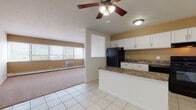 Located at 26101 Country Club Blvd in North Olmsted, Ohio, this single-floor unit offers a practical and well-appointed layout designed for comfortable everyday living. The open-concept kitchen flows seamlessly into the living area, creating a connected and functional space. The kitchen is equipped with black appliances, including a refrigerator and range, complemented by white shaker-style cabinetry, a granite-style countertop, and a peninsula that doubles as a breakfast bar. Light tile flooring runs throughout the kitchen area, while warm neutral carpet extends into the spacious living room. The living room is bright and airy, featuring a ceiling fan with light fixture, a wall-mounted air conditioning unit, baseboard heating, and large windows dressed with horizontal blinds that invite natural light and offer views of the surrounding North Olmsted landscape. The bedroom is generously sized with plush carpeting and includes a double bi-fold closet offering ample storage. The full bathroom features tile flooring, a tub-shower combination with white tile surround, a white vanity with granite-style countertop, and a well-lit mirror above the sink. The unit's warm tan accent walls and clean white trim contribute to a cohesive, inviting ambiance throughout.