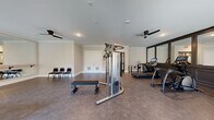 Located at 1670 Friendship Rd in Hoschton, GA, this fitness center offers a comprehensive workout facility within a single, open floor plan. The space is thoughtfully designed with crown molding, recessed lighting, and multiple ceiling fans that contribute to a clean, polished aesthetic throughout.

The main workout area is equipped with a multi-function cable machine, treadmills, an elliptical, a stationary bike, and a flat bench, providing a well-rounded selection of cardio and strength training equipment. A dedicated free weights section includes a dumbbell rack and exercise balls, supported by a large wall-mounted mirror that enhances the sense of space and allows for form monitoring during workouts.

A separate, open studio area features a wide mirror wall with a ballet-style barre, durable flooring ideal for stretching or group exercise, and direct access to the outdoors through glass-paneled doors that invite ample natural light. Additional seating along the walls accommodates users before or after exercise.

The fitness center is accessed through elegant black-framed glass doors and benefits from large windows that frame outdoor views, filling the space with natural light. The durable flooring throughout is both functional and visually cohesive, tying the entire facility together into a well-organized and inviting environment suited for a full range of fitness activities.
