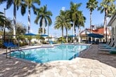 Located at 1351 S Federal Hwy in Boynton Beach, FL, this 1,240 sq ft single-floor condo offers 2 bedrooms, 2 bathrooms, and a practical, well-designed layout. Wood-look flooring flows throughout the main living areas and bedrooms, complemented by crisp white walls that create a bright, clean aesthetic. The open kitchen features rich dark cabinetry, white quartz countertops, stainless steel appliances including a range, microwave, and refrigerator, and wood-look flooring that ties seamlessly into the living space. The spacious living room includes a ceiling fan, a sliding glass door with outdoor views, and ample natural light. The primary bedroom, at 200 sq ft, offers high ceilings, multiple windows with outdoor views, and access to a dedicated walk-in closet with wire shelving. A second walk-in closet provides additional storage. Both bathrooms feature tile flooring, dark vanity cabinetry, quartz countertops, and a tub-shower combination. The dedicated in-unit laundry room houses a full-size washer and dryer with overhead wire shelving. This well-appointed condo delivers functional living with modern finishes throughout.