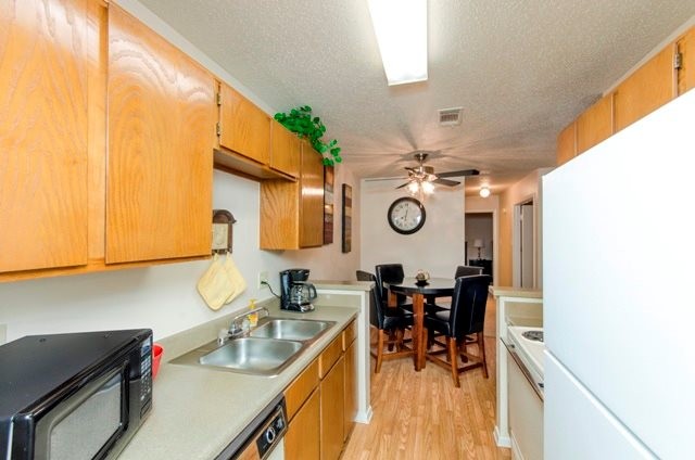 Kitchen with Hardwood-Style Flooring, Wood Cabinetry, and White Kitchen Appliances - City Pines