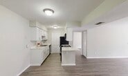 This single-floor, 2-bedroom, 2-bathroom residence offers a thoughtfully laid-out floor plan that maximizes functionality and comfort. The kitchen serves as a central highlight, featuring white shaker-style cabinetry, light granite-style countertops, a stainless steel sink with dishwasher, and black appliances including a gas range with over-the-range microwave. A central kitchen island provides additional counter space and opens toward the living area, creating a seamless flow ideal for everyday living. Consistent wood-look flooring runs throughout the home, lending a clean, cohesive aesthetic to each room. The living room is spacious and bright, with a ceiling fan and access to an outdoor area via a sliding glass door. Both bedrooms are well-proportioned, with neutral sage-toned walls, wood-look flooring, ceiling fans, and window blinds that allow for natural light control. The primary bedroom offers a comfortable footprint with ample room for furnishings. The bathrooms are functional and clean, with one featuring a full tiled tub-shower combination with brushed nickel fixtures. A closet provides dedicated storage. The overall palette of soft neutrals and white trim gives the home a fresh, move-in-ready feel.