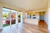 Located at 2731 Rucker Ave in Everett, WA, this well-appointed 2-bedroom, 2-bathroom residence offers a thoughtfully designed single-level layout. The open-concept living, dining, and kitchen area serves as the heart of the home, bathed in natural light from expansive floor-to-ceiling sliding glass doors that frame beautiful views of lush, colorful landscaping. The kitchen features light wood cabinetry, stainless steel appliances including a refrigerator, microwave, and range, a central island with a built-in sink, and stylish pendant lighting overhead. Light-toned hardwood flooring flows seamlessly throughout the entire unit, lending a clean and cohesive aesthetic. Both bedrooms are generously proportioned, each with large sliding glass doors that open to striking views of the surrounding neighborhood and the water beyond. The two bathrooms are clean and functional, featuring light wood vanities with stone-topped counters, large mirrors, and tiled tub-shower combinations. A dedicated hallway connects the living spaces to the private quarters, with a closet providing additional storage. The overall ambiance is bright, modern, and airy, ideal for comfortable everyday living in a prime Everett location.