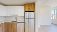 Located at 416 Vine St in Philadelphia's vibrant Old City neighborhood, this thoughtfully designed one-bedroom, one-bathroom unit offers a modern living experience within a compact, efficient floor plan. Light-toned hardwood flooring flows throughout, lending warmth and visual continuity across every room.

The living room is anchored by expansive multi-pane windows that frame views of the surrounding historic streetscape, filling the space with generous natural light. The kitchen is a standout feature, showcasing a clean, contemporary design with two-tone cabinetry — crisp white uppers paired with warm wood-grain lower cabinets — accented by brushed gold hardware. Stainless steel appliances, including a refrigerator, range, microwave, and dishwasher, complete the well-appointed cooking space, all set against a classic white subway tile backsplash.

The bedroom is spacious and bright, featuring large windows with open views that include glimpses of the Philadelphia skyline. Two closets provide ample storage. The bathroom is sleekly finished with a floating wood-tone vanity, white countertop, large-format floor tile, and a glass-enclosed walk-in shower clad in vertical mosaic tile. A dedicated laundry area and utility room add everyday convenience to this polished urban residence.